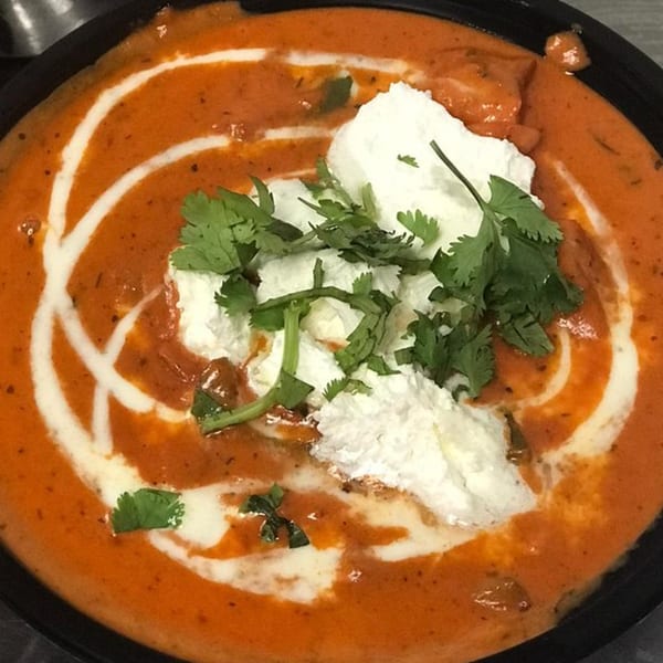 Heart of India's butter chicken, a rich orange curry with cream swirls and fresh cilantro.